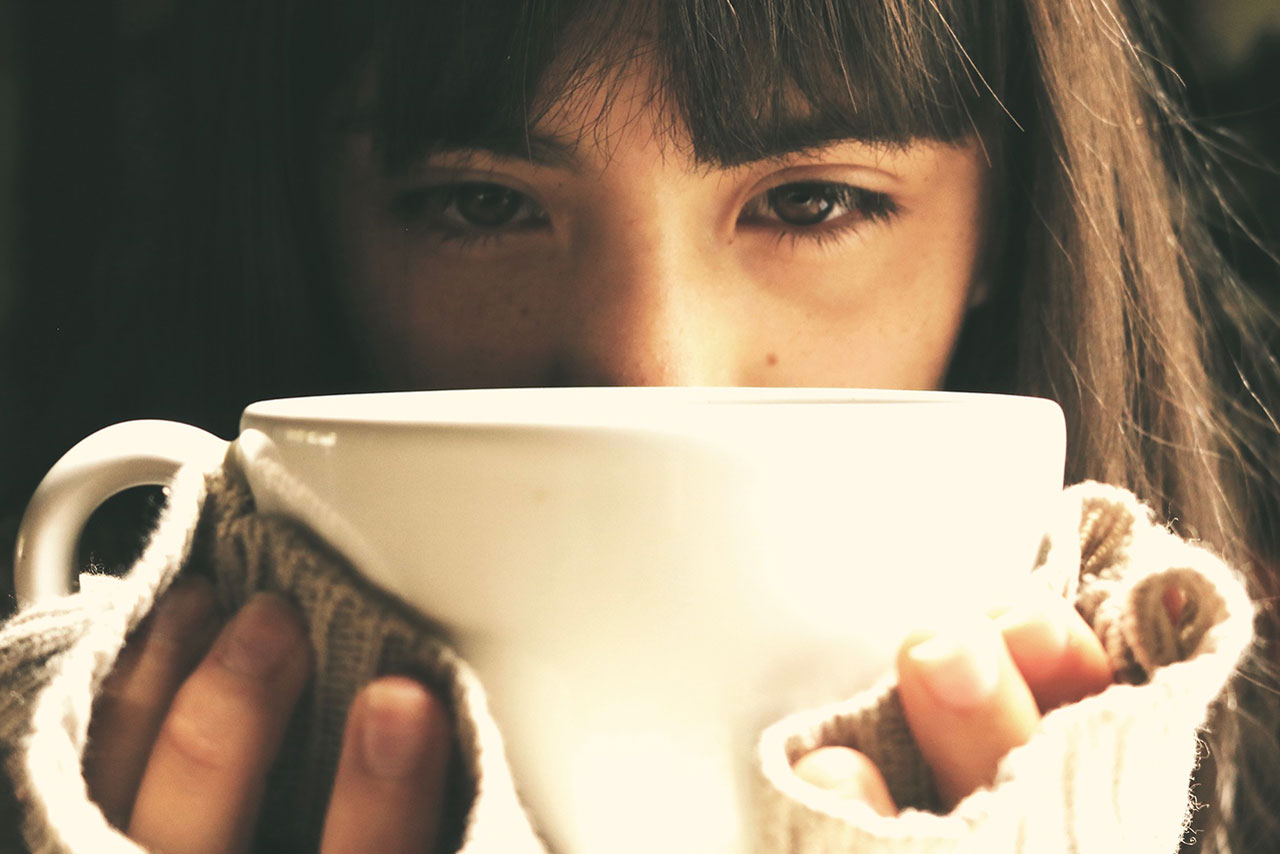 Picture of a depressed woman drinking from a cup of coffee