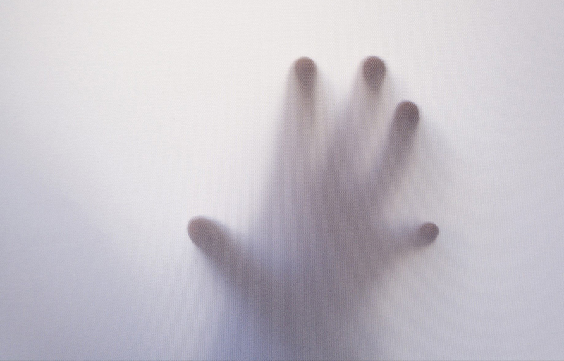 Hand pressing against a screen in desperation showing things beyond your control.