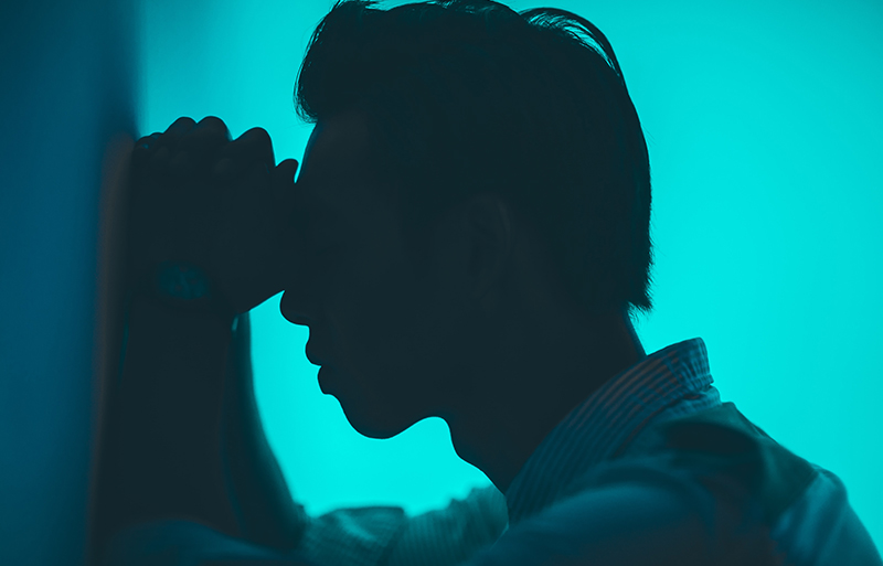 Picture of a man feeling depressed leaning against a wall