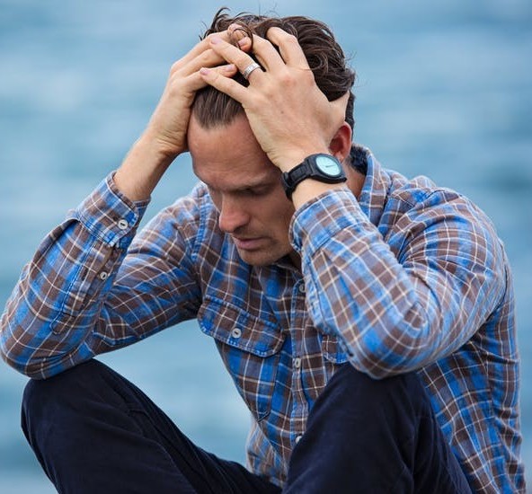 A man sitting with knees up and hands holding his head