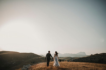 A couple in wedding clothes walking off in the horizon